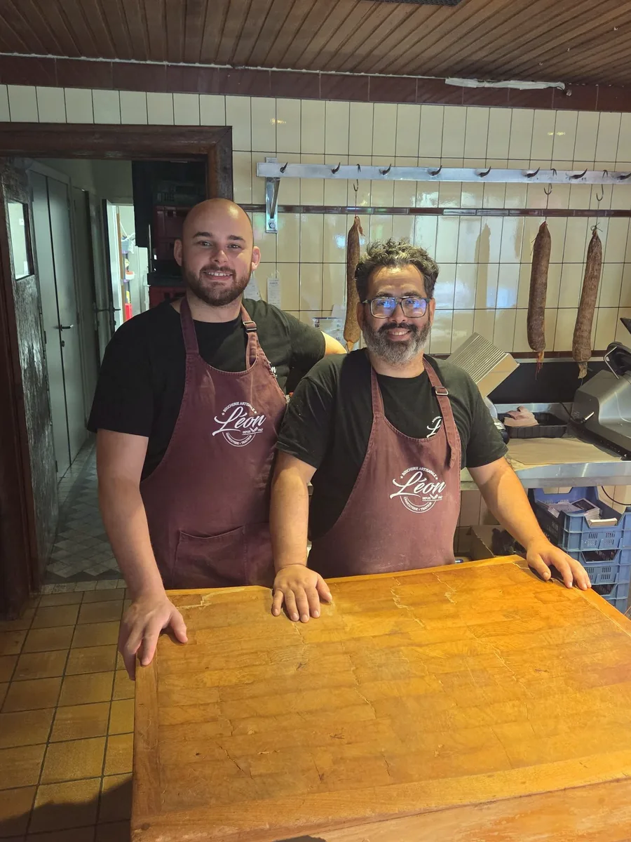 Les deux bouchers de la Boucherie Léon en tablier bordeaux, derrière le billot.